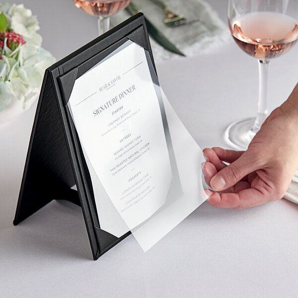 A hand holding a menu on a table.