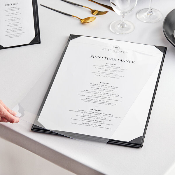 A hand placing an Acopa clear vinyl sheet protector with a menu on a table.