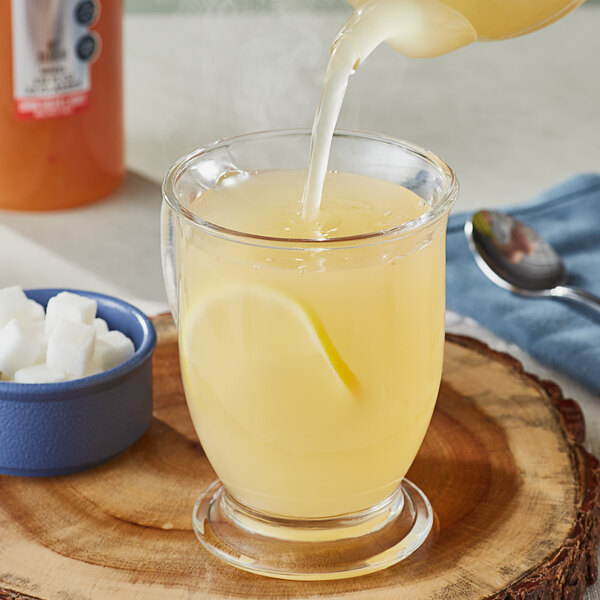 A person pouring SHOTT Lemon, Ginger, and Honey syrup into a glass of liquid.