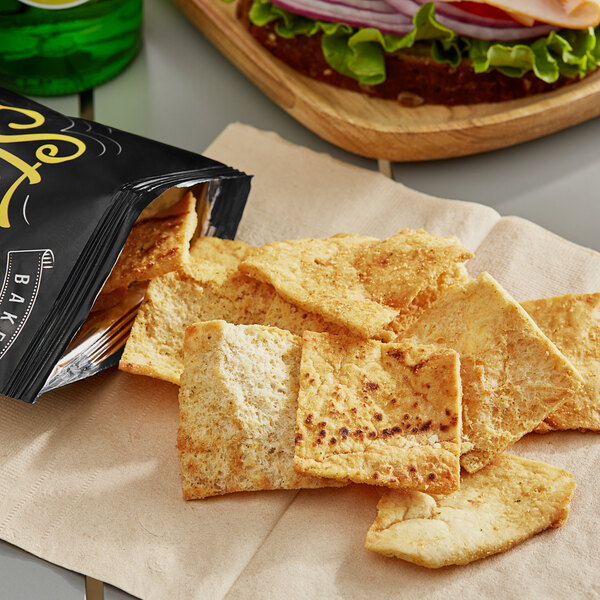 A bag of Stacy's Parmesan, Garlic, and Herb Pita Chips on a napkin next to a sandwich.