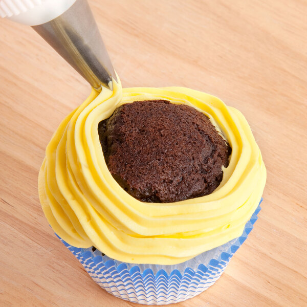 A cupcake with yellow icing piped on using an Ateco open star piping tip.