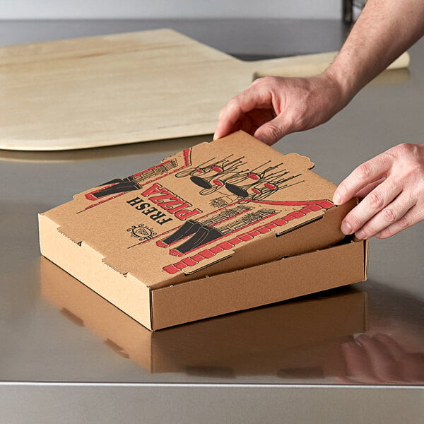 A person opening a Choice kraft corrugated pizza box on a table.