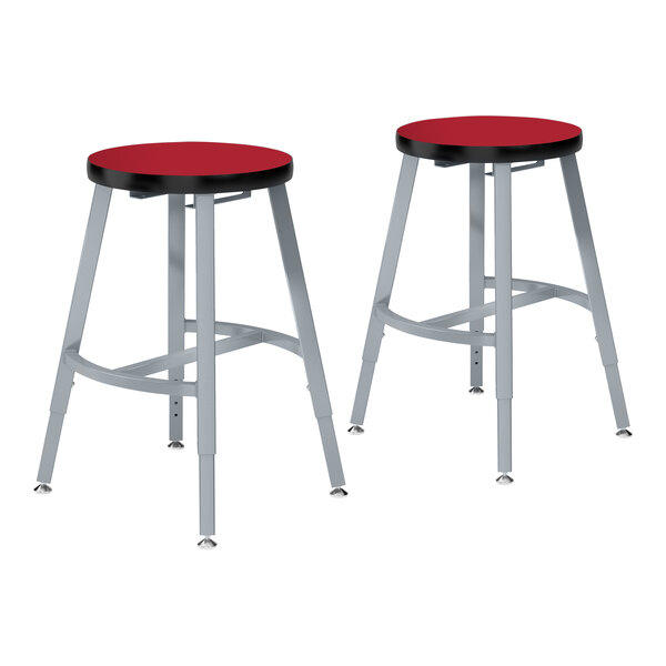A pair of National Public Seating black and silver lab stools with red high-pressure laminate seats.