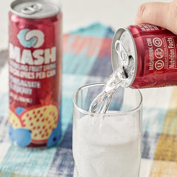 A hand pouring Boylan Mash Pomegranate Blueberry soda from a red can into a glass.
