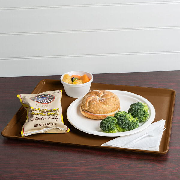 A tray with a sandwich, broccoli, and potato chips on a table.