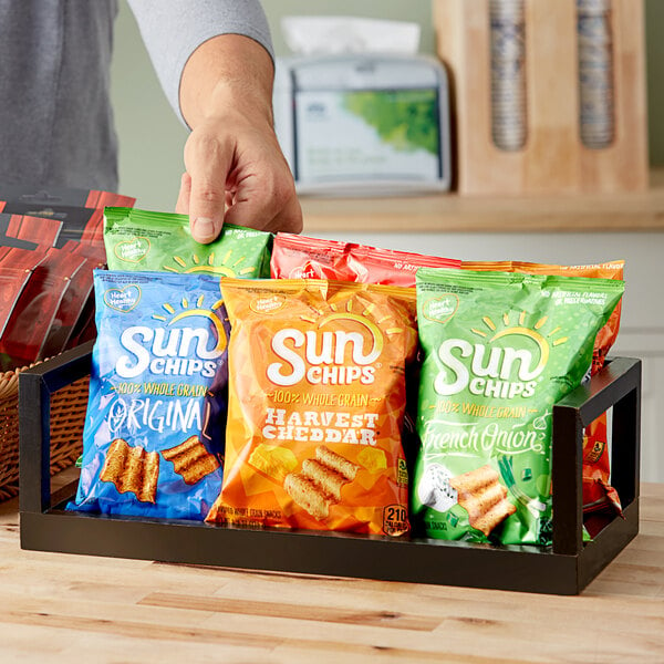 A person holding a tray of Sun Chips snacks.