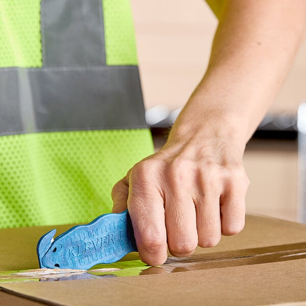 A person using a Klever Kutter metal box cutter to open a blue box.