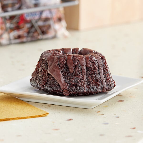 A Ne-Mo's Bakery individually wrapped mini chocolate bundt cake on a plate.