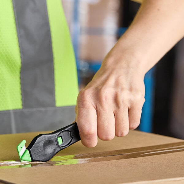 A person using a green and black Klever Kutter EcoXChange to open a box.
