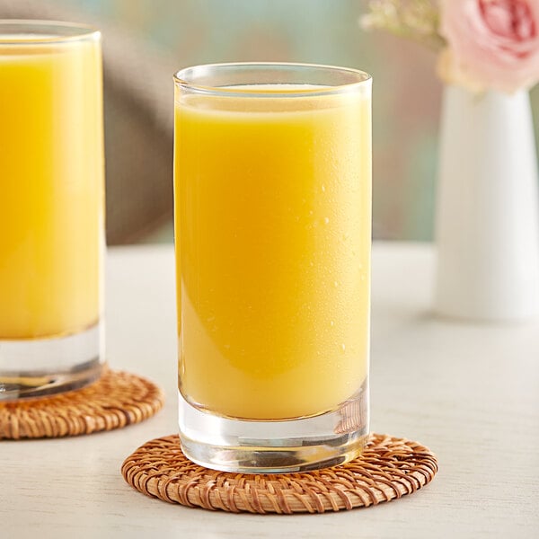 Two glasses of Hartley's orange juice on a coaster.