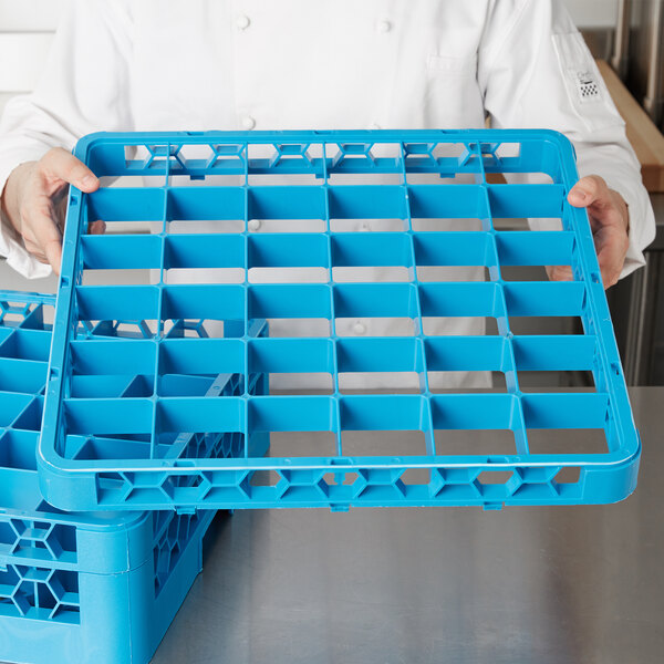 A person holding a blue Carlisle plastic glass rack extender.