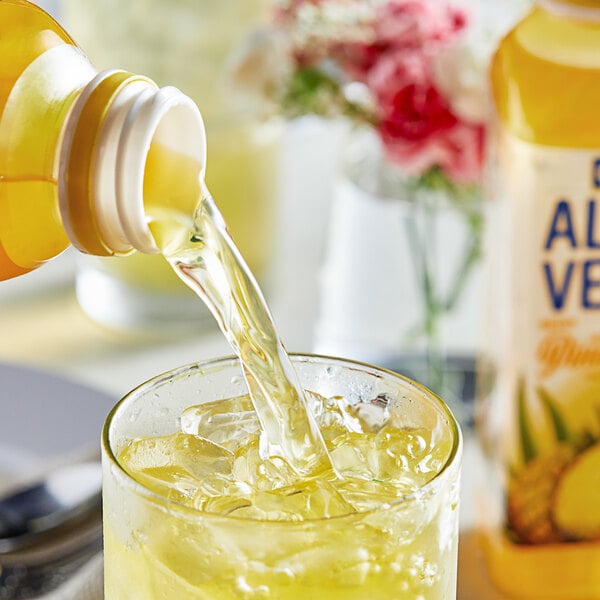 A Goya Pineapple Aloe Vera Drink bottle pouring liquid into a glass with ice.