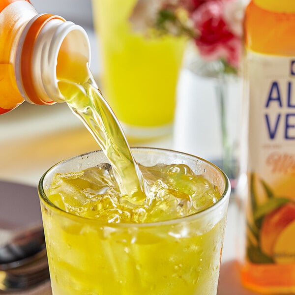 A bottle of Goya Mango Aloe Vera drink pouring into a glass with ice.