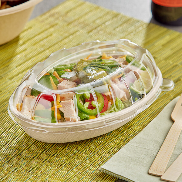 A plastic container with a salad and wooden fork and knife in it.