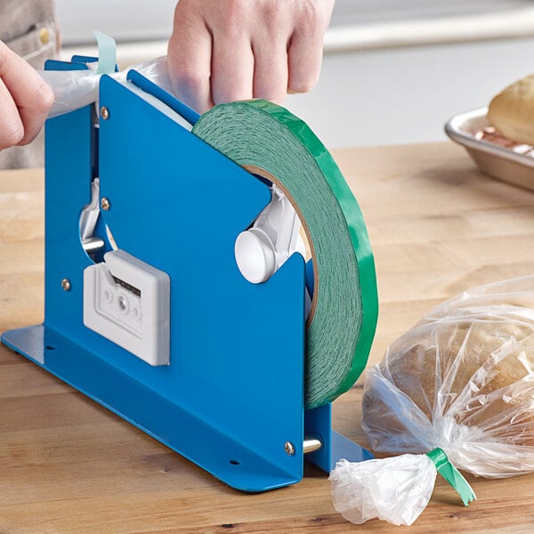 A blue tape dispenser with a Lavex green tape roll being used to seal a bag of bread