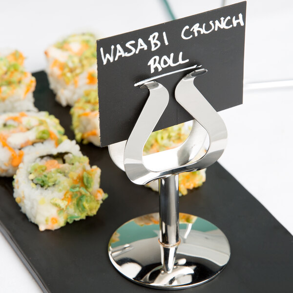 A sushi plate with a Tablecraft stainless steel harp menu holder on it.