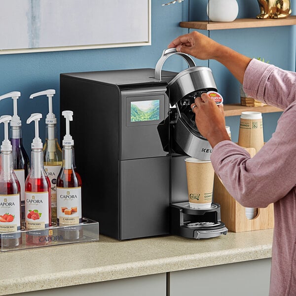A woman using a Keurig K-3500 plumbed coffee machine to make coffee.