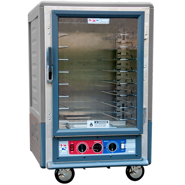 A gray Metro C5 heated holding and proofing cabinet with clear glass doors and wheels.