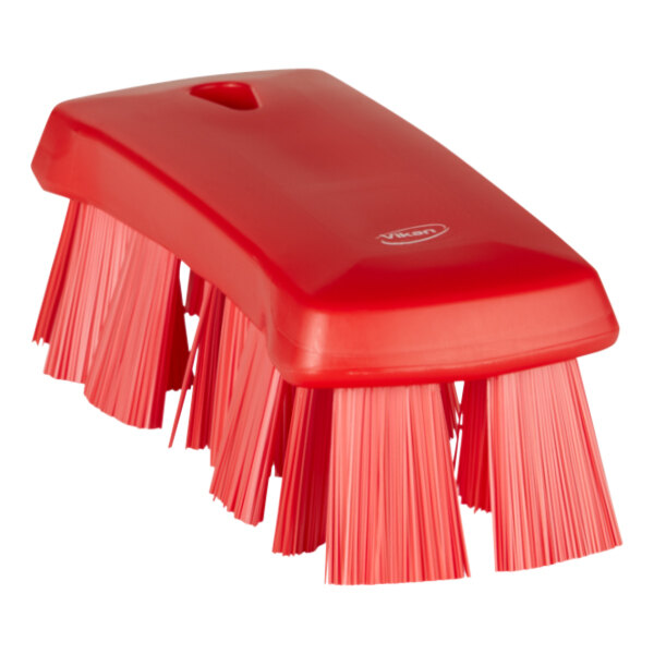 A close-up of a Vikan red hand brush with stiff bristles.