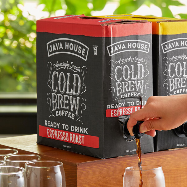 A person pouring Java House Espresso Roast Cold Brew Coffee from a box into a glass.