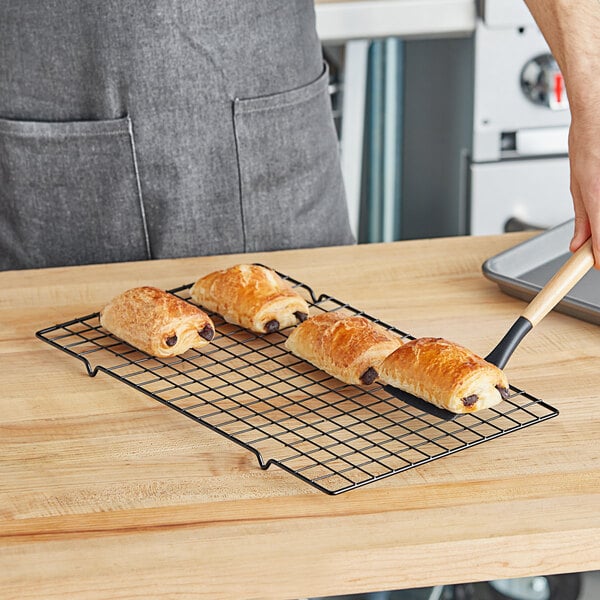 A person holding a pastry on a Wilton cooling rack.
