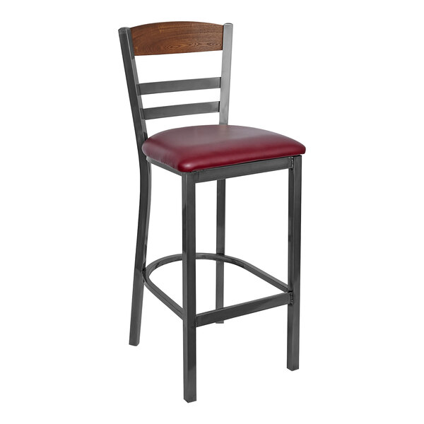 A BFM Seating clear coated steel barstool with a burgundy vinyl seat and wood back.