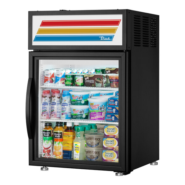 A black True countertop refrigerator with drinks and yogurt behind glass doors.