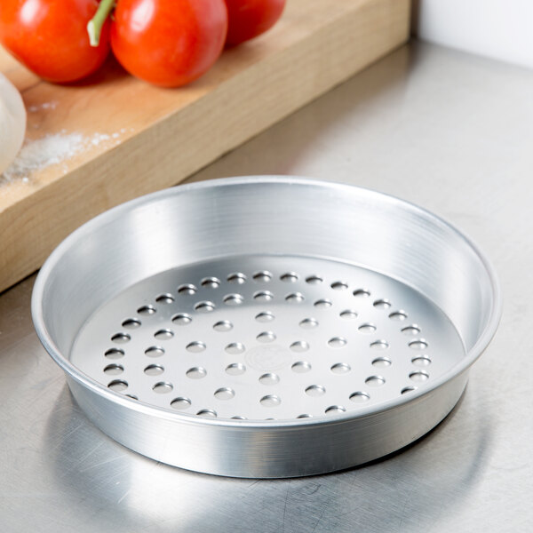 An American Metalcraft round silver pizza pan with holes in it.