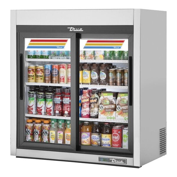A True stainless steel countertop glass door refrigerator with various drinks inside.