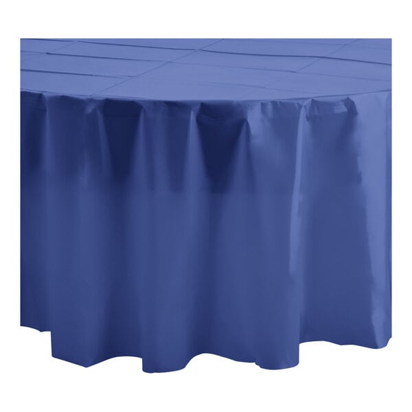 A close up of a navy blue Table Mate round plastic tablecloth on a white surface.