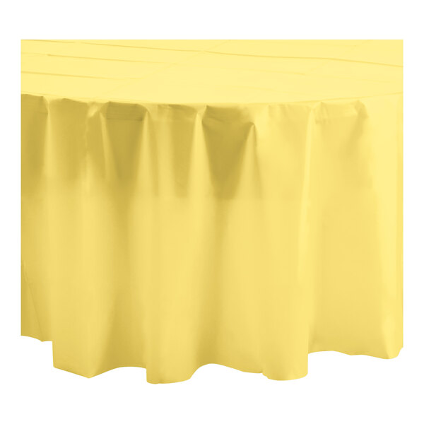 A yellow round Table Mate plastic table cover with ruffled edges on a white surface.