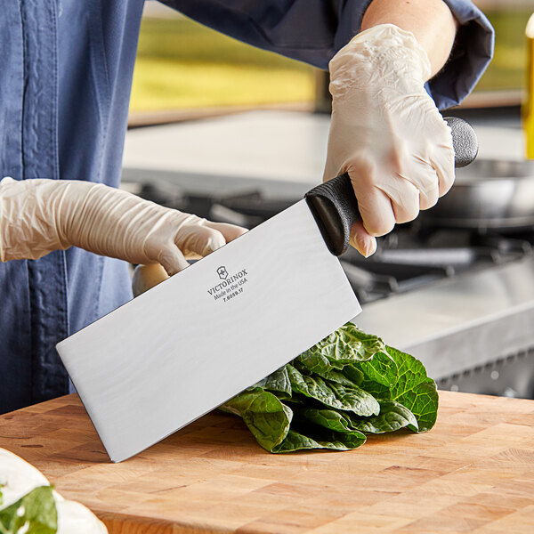A person using a Victorinox Chinese Cleaver to cut leafy greens.
