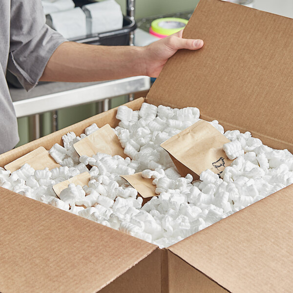 A person opening a box full of white Lavex foam packaging peanuts.