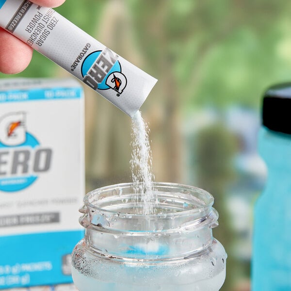 A hand pouring Gatorade Zero Sugar Glacier Freeze powder into a glass jar.