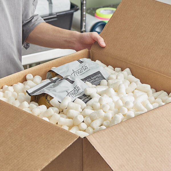 A person holding a box full of white foamy packing peanuts.