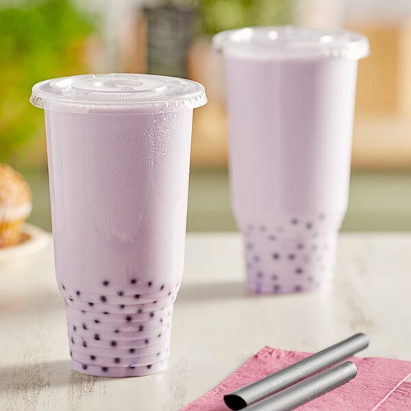 Two clear Choice PET plastic cups of bubble tea with straws.