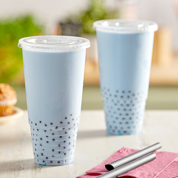 Two clear plastic Choice cups with straws on a table.