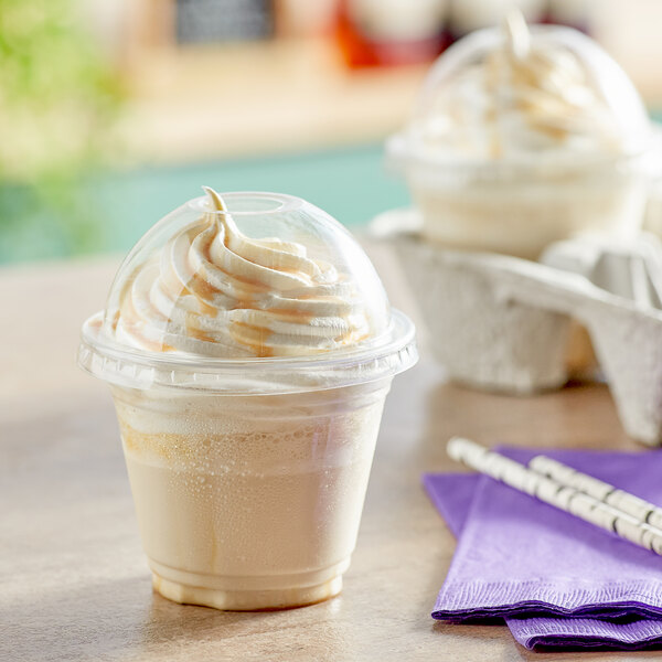 A close up of two Choice clear plastic cups with whipped cream and straws.