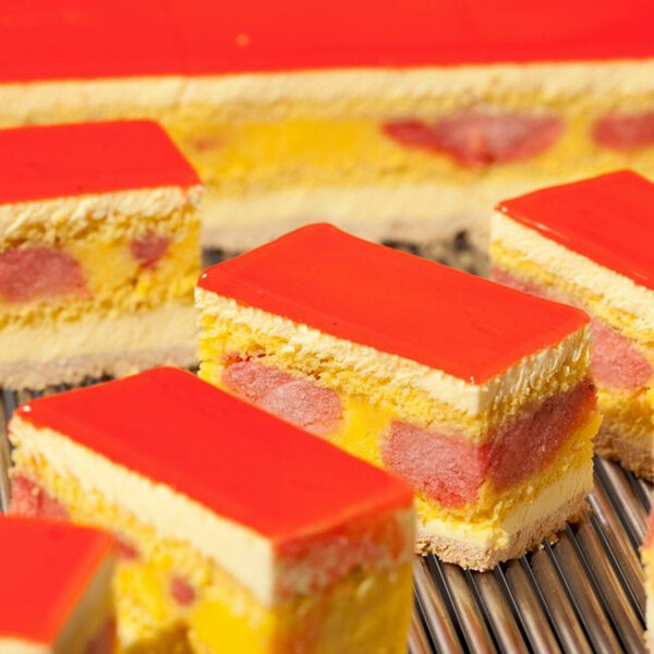 A close up of several slices of cake with a red and yellow background cut with a Pavoni LT35H6 Cutting Frame.