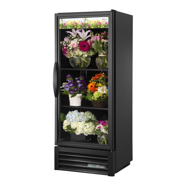 A black refrigerator with flowers on shelves.