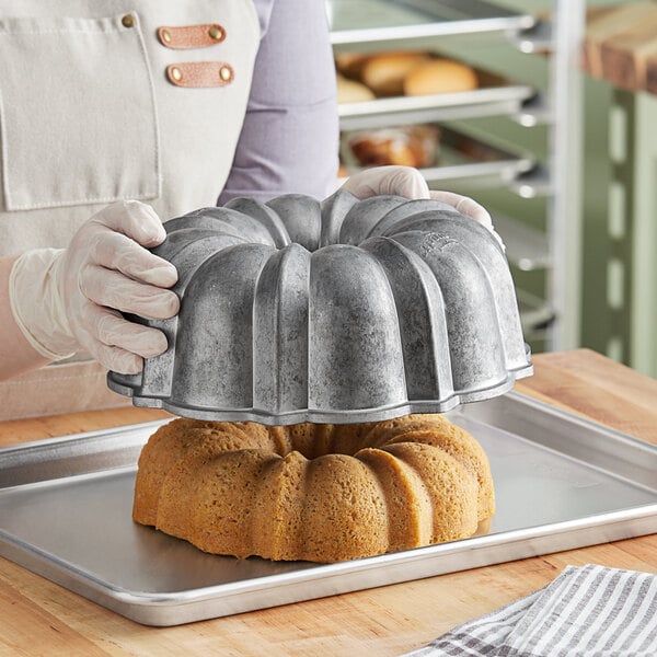 A woman holding a tray with a Nordic Ware Bundt cake.
