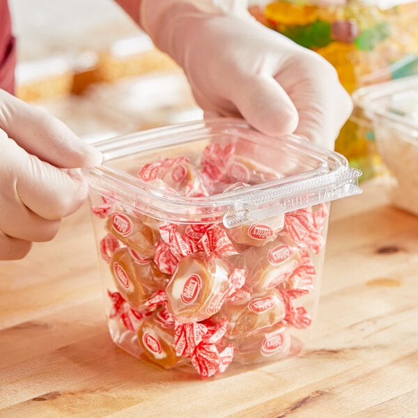 A person in gloves holding a Inline Plastics Safe-T-Fresh plastic container of candy.