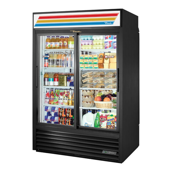 A black True refrigerated merchandiser with a glass door full of drinks and beverages.