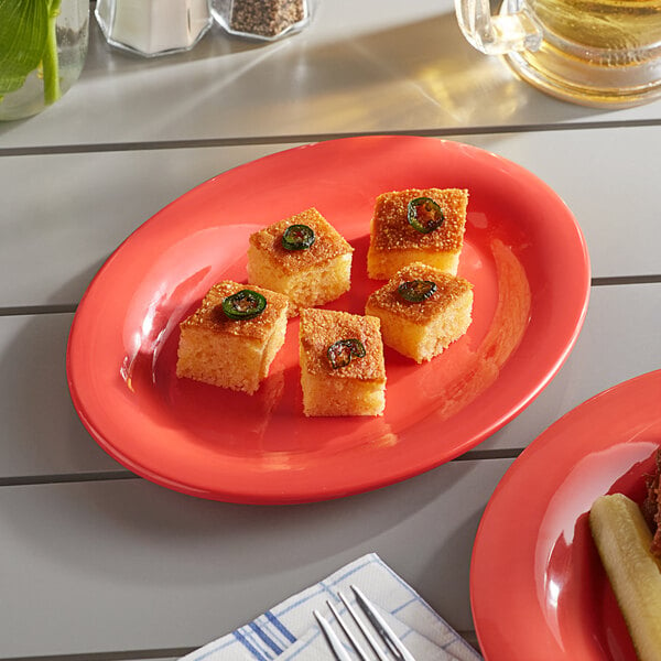 An Acopa orange melamine platter with food on a table.
