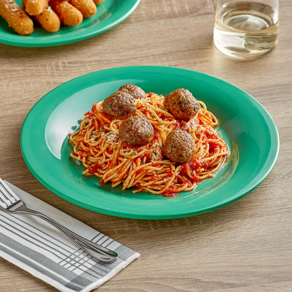 A plate of spaghetti and meatballs on a green Acopa Foundations melamine plate.