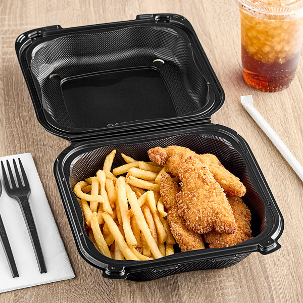 A black plastic Genpak hinged container with food inside on a table.