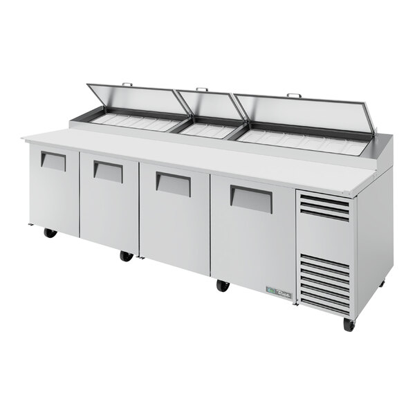A True refrigerated pizza prep table with four open doors on a counter.