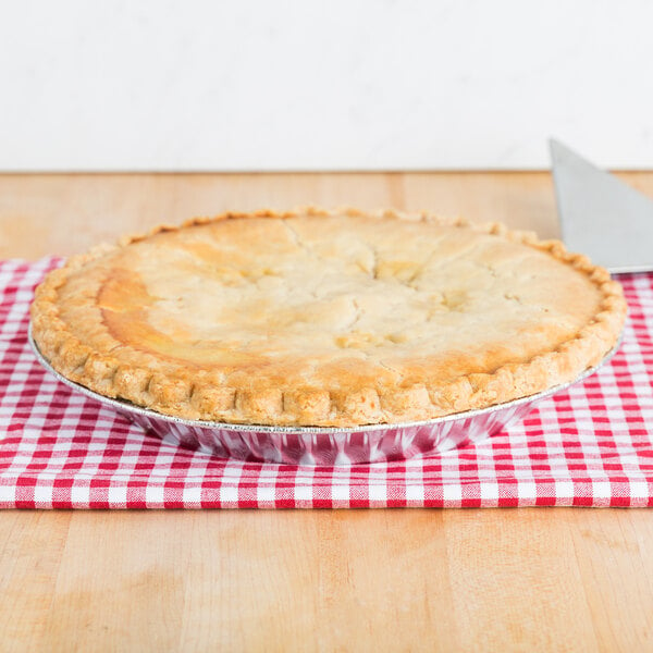 A Baker's Lane pie in a foil pie pan on a red and white checkered tablecloth.