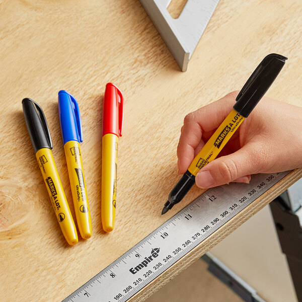A hand holding an Avery Marks-A-Lot yellow permanent marker over a ruler.