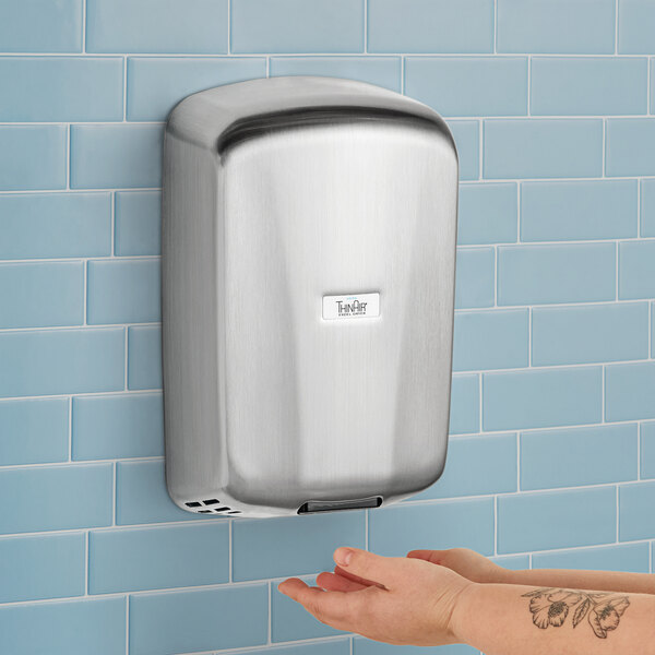 A person using an Excel ThinAir high-efficiency hand dryer with brushed stainless steel cover.